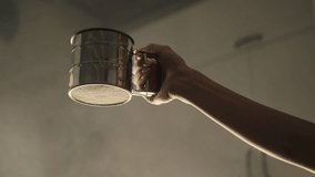 Slowmotion of woman is sifting flour through a metal sifter, hand closeup view. Preparing flour for baking cake in kitchen at home. High quality 4k footage - Powered by Shutterstock - Get 15% off with code: PIKWIZARD15