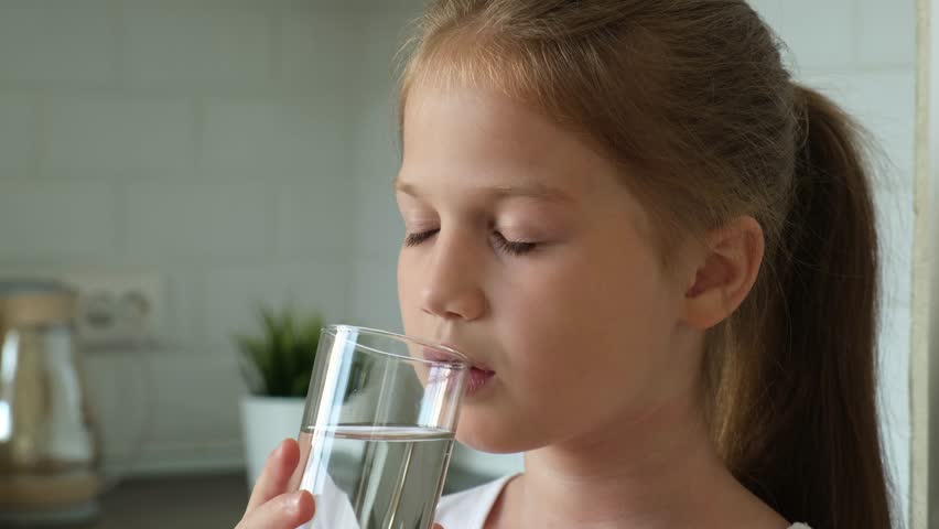 Little girl drinking water from glass in the kitchen at home. Closeup child drinks cup of fresh pure filtered clean water indoors. Healthy body care for children. Slow motion Royalty-Free Stock Footage #1099381935