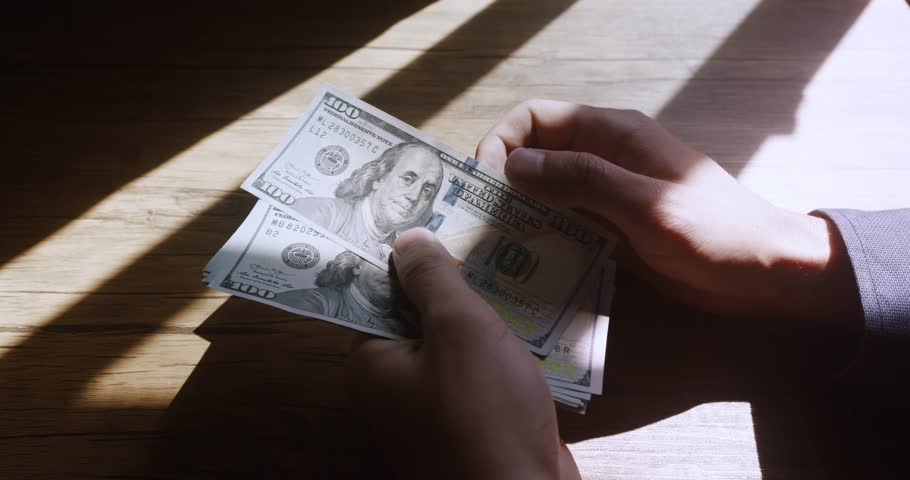 Close-up of American US dollars in hands, counting money. Business person sitting at the table, counts earned money, fixing profits. Business man calculates 100 usd banknotes in hands Royalty-Free Stock Footage #1099381975