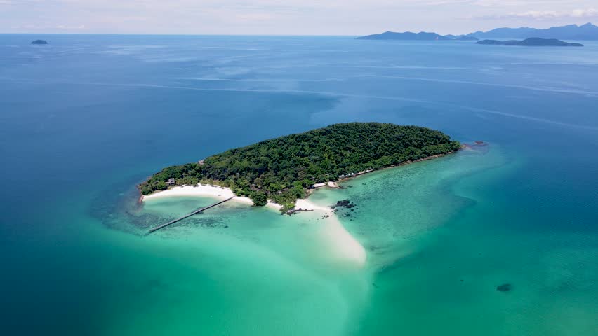 Tropical Island in Thailand with palm trees and black stones in the ocean of Koh Kham near Koh Mak. 
