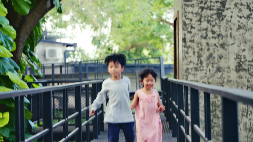 2 children Asian brothers and sisters Run hand in hand on outdoor playground. There