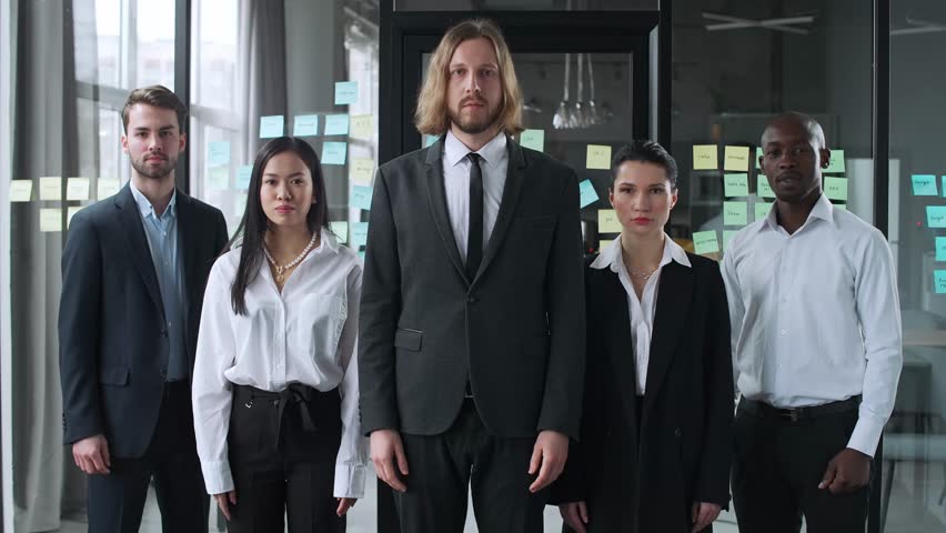 International office team stands and looks at the camera, a serious team of financial analysts, interior of the office against the background. | Shutterstock HD Video #1099388297