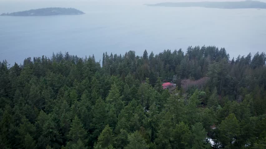 View of islands in the Georgia Straight tilted down to see patches of snow and homes among the forest tress
