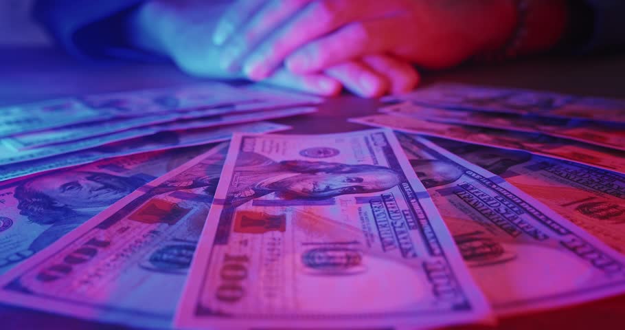 Close up lucky male winner hands grabbing bunch of dollars lying on casino table in neon light. Happy winner received winnings money at casino. Man win cash money in gambling or lottery. Easy money Royalty-Free Stock Footage #1099390373