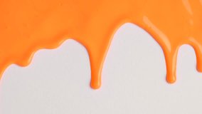 Liquid drops of orange paint color flowing on the white surface. Macro shot of orange paint dripping on the white wall with copy space. Production Close-up. Slow Motion, Abstract art.  - Powered by Shutterstock - Get 15% off with code: PIKWIZARD15