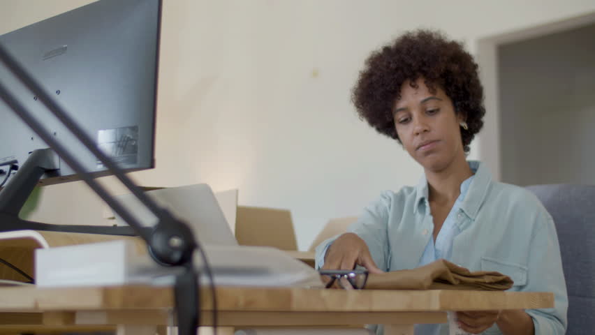 Serious Black woman checking clothing quality and barcode on computer, and then packing item in cardboard parcel. Female webstore owner making delivery preparations. Startup, online store concept | Shutterstock HD Video #1099392283