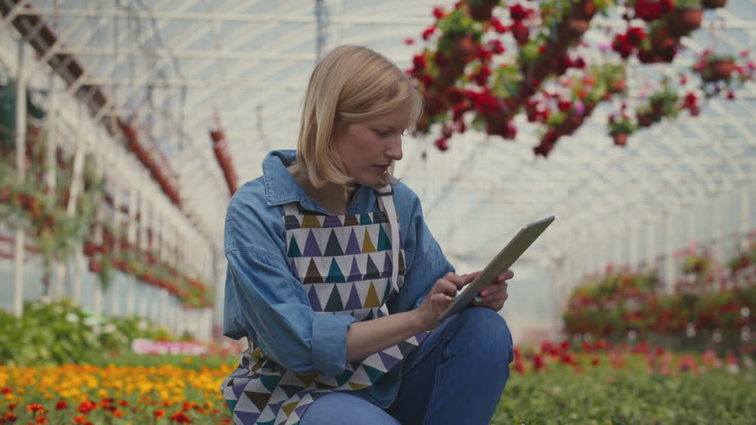 Woman counting flowers with a help of digital tablet.
