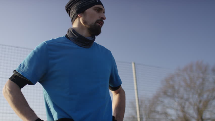 Basketball player talking to someone off camera on an outdoor court in the cold, in slow motion
