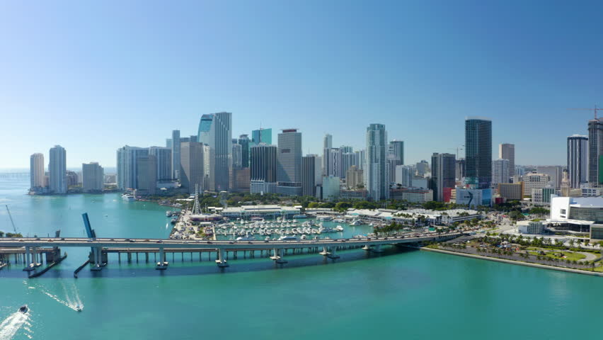 Aerial view of futuristic urban tall buildings and skyscrapers. Multilane road bridge above turquoise water in river. Modern downtown skyscrapers along Miami river. High rise office. Miami. USA. 