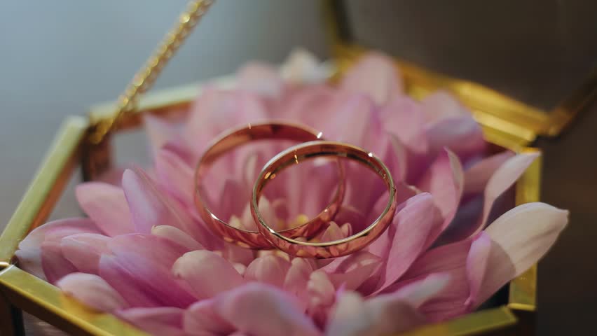 Two gold rings lie on top of beautiful flowers. Shooting a cool composition | Shutterstock HD Video #1099398049