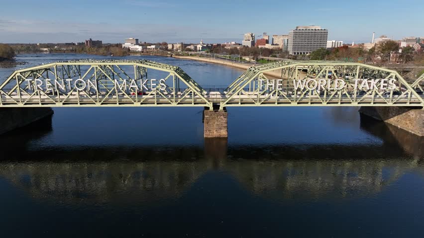 Bridge over Delaware River between Trenton New Jersey and Morrisville Pennsylvania. Rising aerial. Trenton Makes, The World Takes sign. Royalty-Free Stock Footage #1099404373