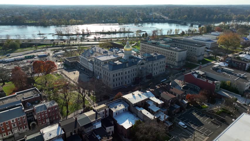 Trenton New Jersey aerial establishing shot with NJ capitol dome. Flight toward Delaware River on autumn day.