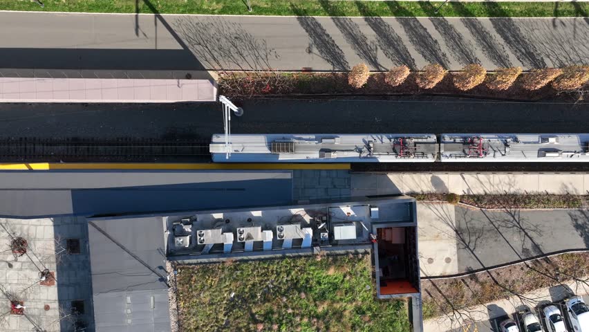 Commuter rail train. Public Transportation in USA. Top down aerial of train station platform arrival and departure.