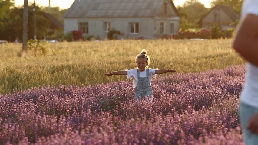 Adorable little girl is having fun and running against the background of a large lavender field on sunset. Hyperactive smiling little kid in sunglasses on nature. International Children's Day. Royalty-Free Stock Footage #1099405635