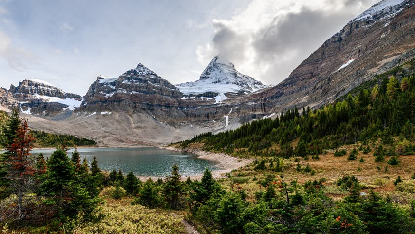Time lapse of Mount Assiniboine famous with blue sky in autumn forest reflection on Lake Magog at Assiniboine provincial park, BC, Canada