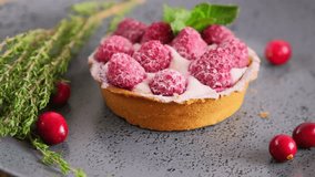 Raspberry tartlet with whipped cream and fresh berries served on a plate, slow motion rotation video, mini tart cake sprinkled with sugar, close up video of sweet dessert, hd video footage
