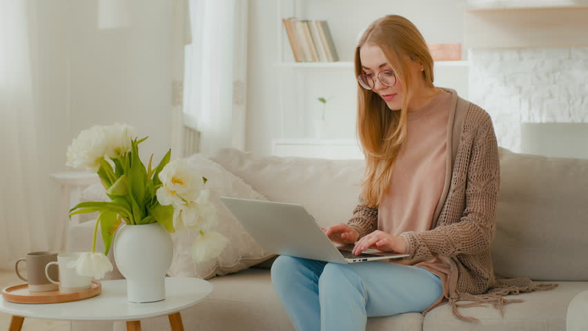 Caucasian woman in glasses happy girl lady student businesswoman freelancer female with laptop sitting on couch celebrating good news exams admission business great results win success victory winning Royalty-Free Stock Footage #1099421665