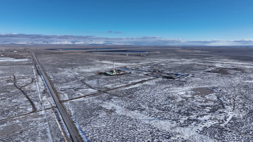DELTA, UTAH - 22 JAN 2023: Aerial desert landscape oil gas well winter snow descend. Large coal fired power plant desert region. Buidings, towers, cooling. Pollution environmental comply with EPA.