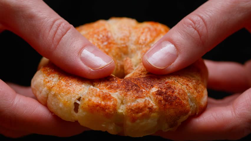 hands breaking pastries from puff pastry. close-up of baking on a black background. slow motion