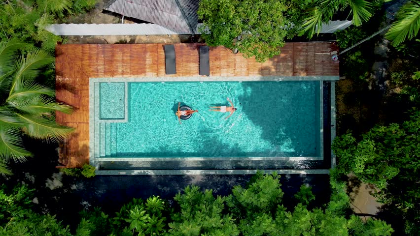 Couple in pool, aerial drone view of a swimming pool in the jungle of Krabi Thailand, aerial view with a drone above swimming pool in the jungle of Thailand. a couple of men and women in pool  | Shutterstock HD Video #1099429471