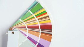 Female Hand opening Color guide close up. Assortment of Colour samples for design. Colors palette fan on white concrete wall background. Graphic designer chooses colors. Coloured swatches catalogue 4K - Powered by Shutterstock - Get 15% off with code: PIKWIZARD15