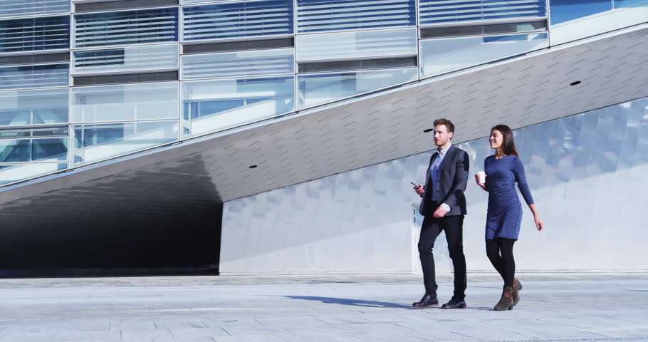 Business people walking and talking - businessman and businesswoman outdoors by office building. Young professional business woman and business man in smart casual clothing. SLOW MOTION | Shutterstock HD Video #1099431291