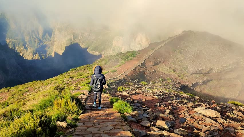 Woman hiker climbs the foggy stairs. Young and fit woman is walking down the trail to the top of Pico do Arieiro, Madeira. Tired woman walking and hiking stone stairs. Fog and mist in the mountains.  | Shutterstock HD Video #1099432013