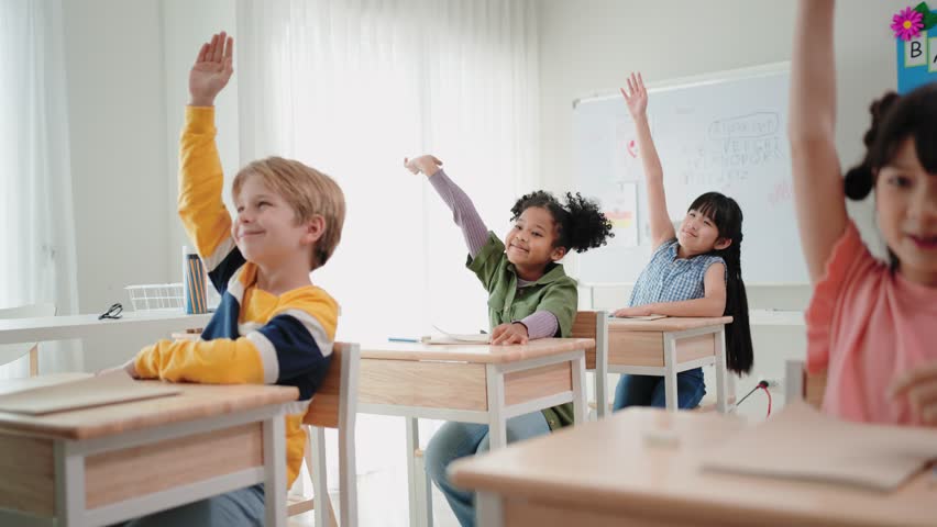 Elementary school students are sitting in the classroom at school and are raising their hands when the teacher asks | Shutterstock HD Video #1099433131