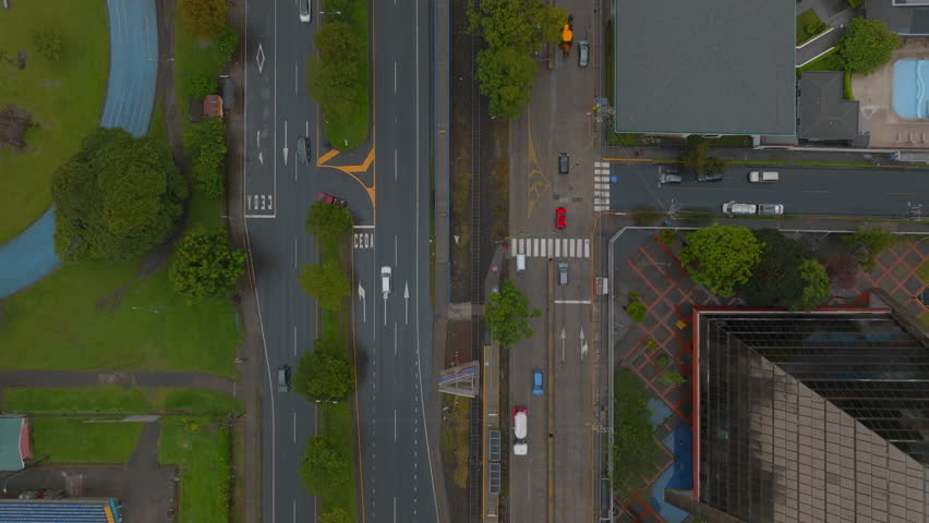 Top down with of low traffic on roads in city. Vehicles driving on multilane road along green park. San Jose, Costa Rica