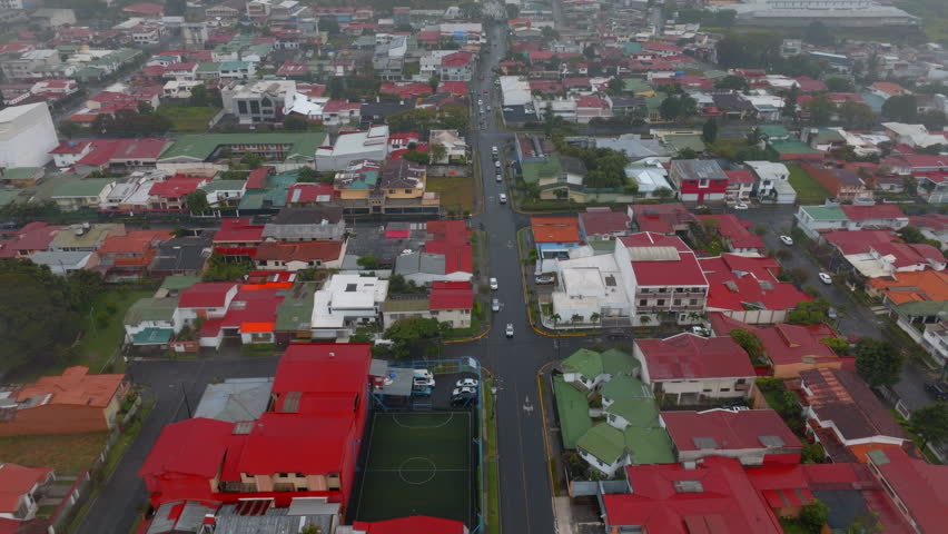 Forwards fly above buildings and streets in residential urban borough on rainy day. San Jose, Costa Rica