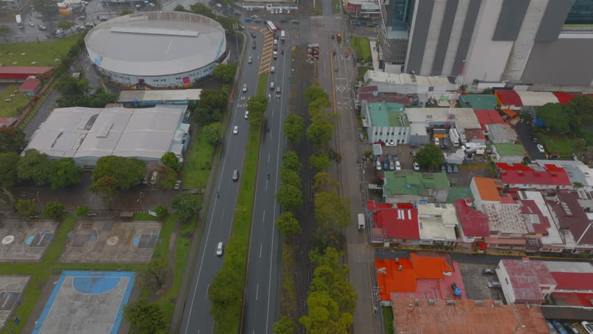 High angle view of traffic in streets of capital. Tilt up reveal hazy view of metropolis. San Jose, Costa Rica