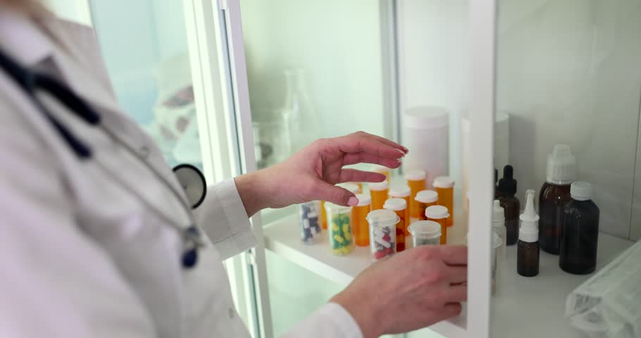 Doctor pharmacist looking for right jar of medicine in closet closeup 4k movie slow motion | Shutterstock HD Video #1099436449