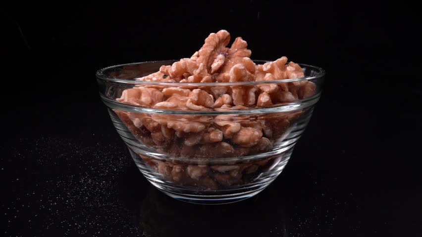 Falling shelled walnuts in super slow motion macro shot into a glass plate. On a black background. | Shutterstock HD Video #1099437649