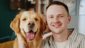 British redhead man together with dog retriever making selfie photo or video call on front camera smartphone. Positive young student man conference call with pet for blog.