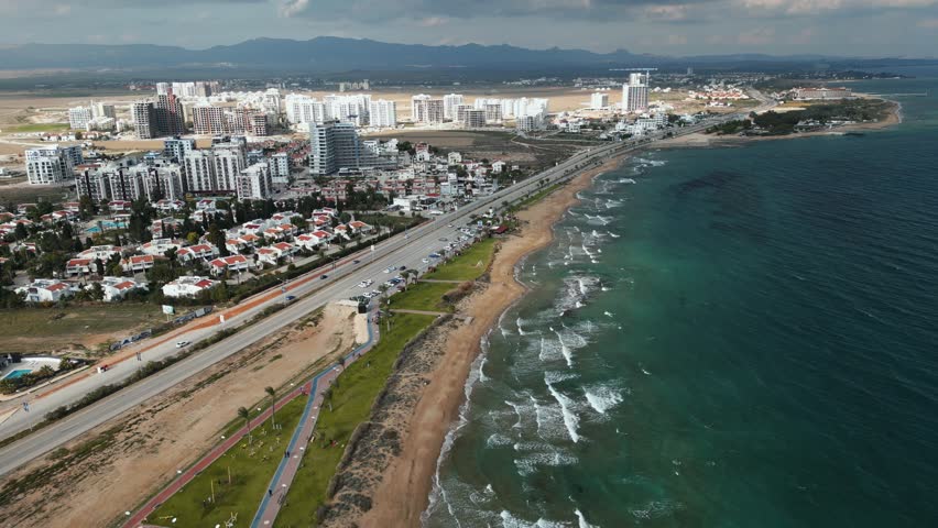 Long Beach (Cyprus). Drone video. Beautiful beach and modern buildings. Blue ocean The long road goes into the horizon. Thunderclouds on the horizon. Blue overcast sky with white clouds.