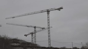 3 cranes construction time lapse. Cranes at the construction site are moving construction work. Moving clouds and an overcast evening sky in the background. A small video for advertising design.