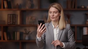 Business smiling woman having video call on smartphone in slow motion. Close up serious business woman making video chat online on mobile phone in office.