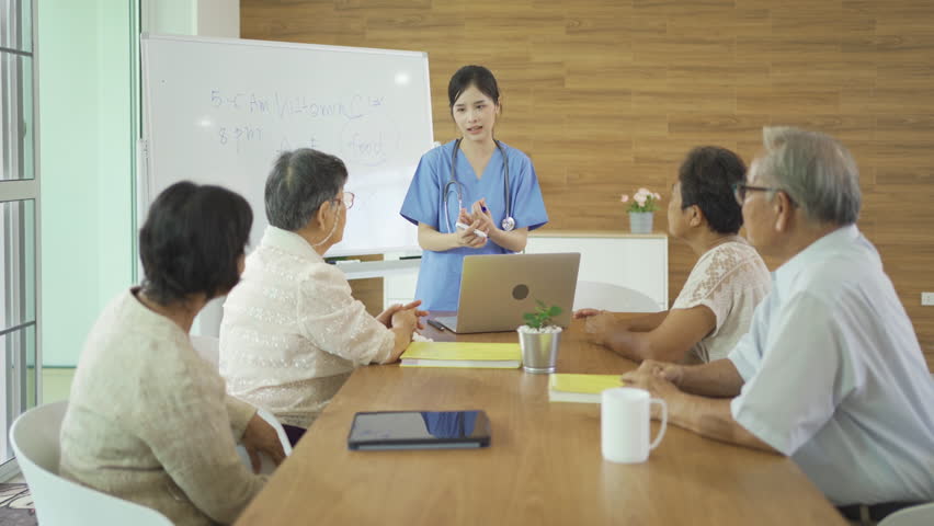 An Asian nurse talking to a group of old elderly patient or pensioner people smiling, relaxing, having fun together in nursing home. Senior lifestyle activity recreation. Retirement. Health care | Shutterstock HD Video #1099448675