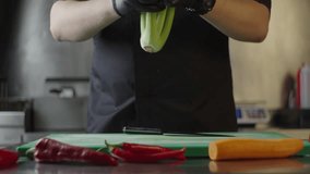 Slow motion close-up video of chef preparing fresh organic celery for slicing. The process of cooking food in the restaurant kitchen.