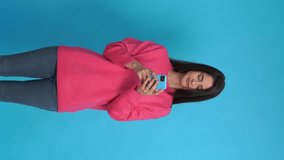 Young woman with smartphone in studio. Vertical video.