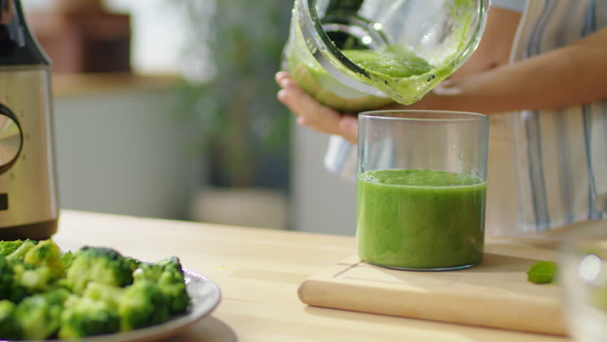 Close up shot of hands of woman pouring freshly made green smoothie from blender into glass Royalty-Free Stock Footage #1099449915