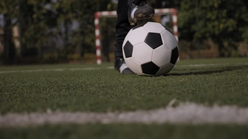 Close-up of a soccer ball on a field with green grass, a little boy puts his foot on the ball. Children's sports Concept. | Shutterstock HD Video #1099451853