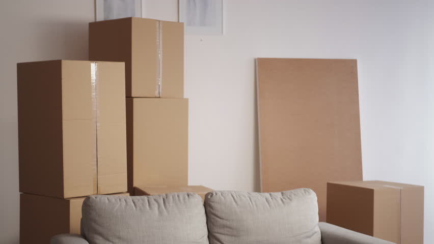 New apartment. Excited man. Enjoying moving. Happy satisfied guy feeling joy sitting sofa with packed cardboard boxes light room interior. | Shutterstock HD Video #1099451981