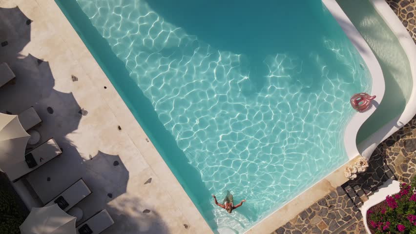 Top view of woman swimming in hotel pool, summer time, drone footage, Turkey