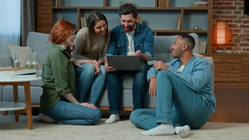 Multiracial team friends ethnicity diversity shoppers sit in living room work with laptop use credit card for online payment ordering delivery service spending money finances internet shopping talking | Shutterstock HD Video #1099456505