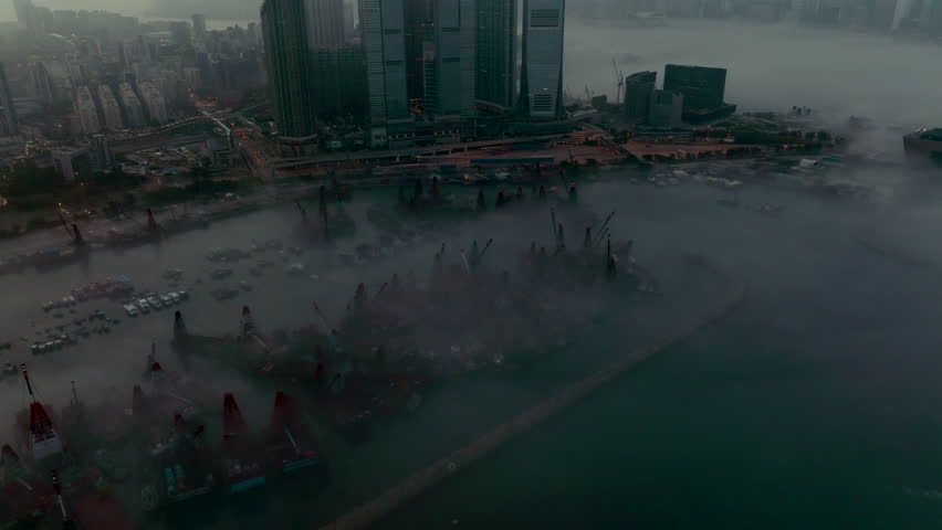 Wide angle slow revealing aerial shot of fog covered West Kowloon with loading crane barges docked in Typhoon shelter, Hong Kong, at dawn | Shutterstock HD Video #1099457973