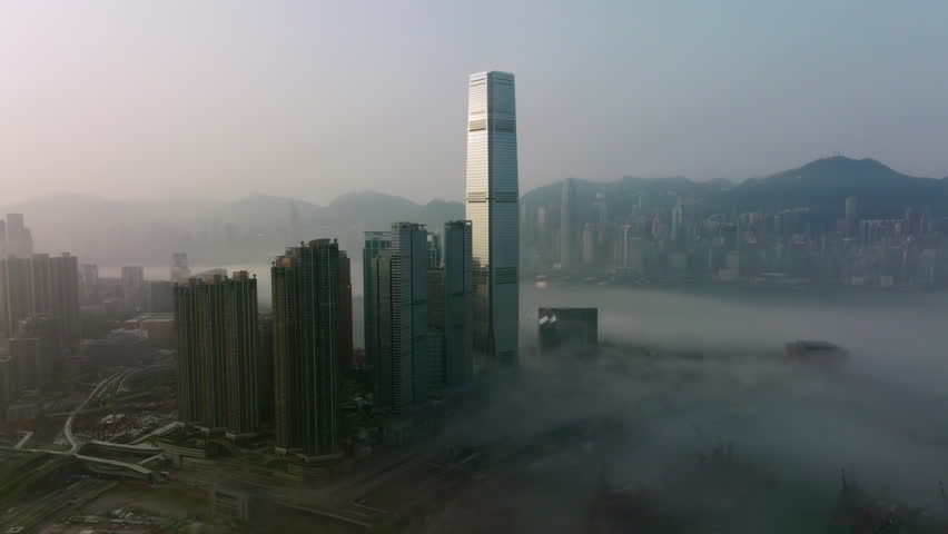 wide angle slow tracking right aerial shot of fog covered West Kowloon high-rise buildings, Hong Kong Island