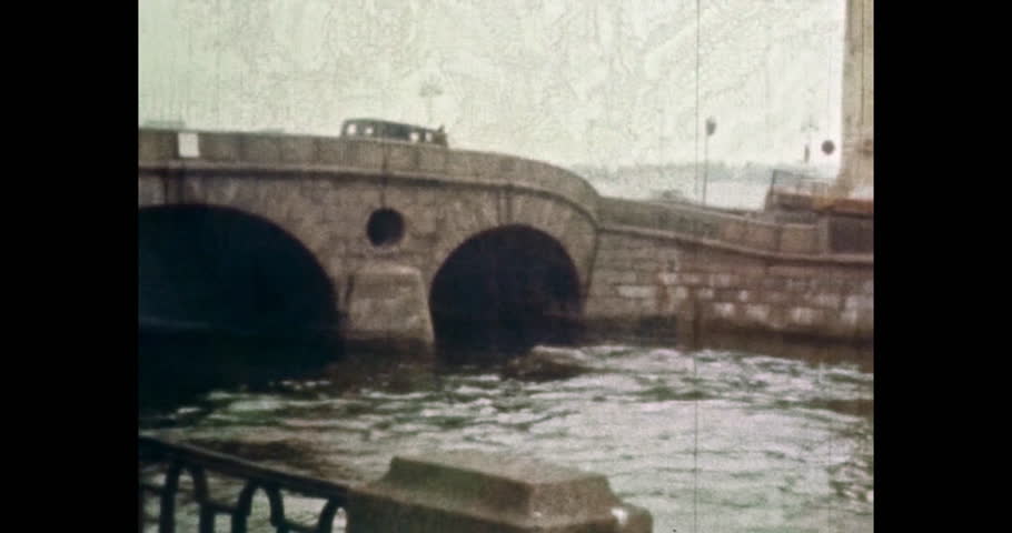 Stone bridge over river in summer Europe city. 1980s Petersburg, Russia. Cars, public buses transport drive across old bridge. City embankment. Old archives. Vintage archival color film. Retro archive | Shutterstock HD Video #1099460909