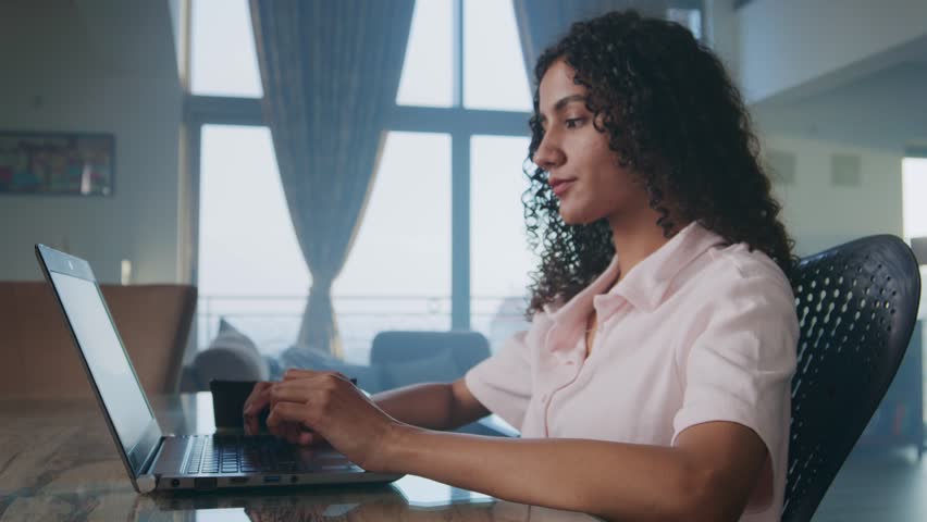 A young modern Indian Asian curly haired independent corporate woman entrepreneur or female start up office employee or worker busy working online from home using a laptop sitting in an interior house Royalty-Free Stock Footage #1099462489