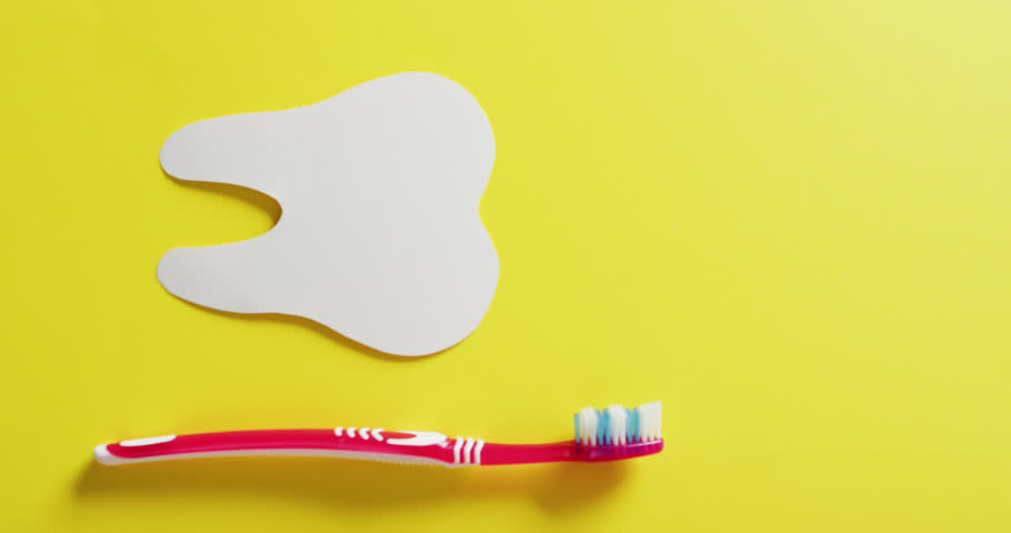 Vertical video of tooth shape and red toothbrush on yellow background, with copy space. Health awareness, dental care, support and healthcare services concept. | Shutterstock HD Video #1099466041